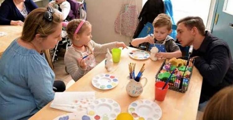 Family sat around a table doing a craft activity